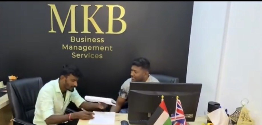 A client consultation at the MKB front desk beneath the gold MKB logo wall